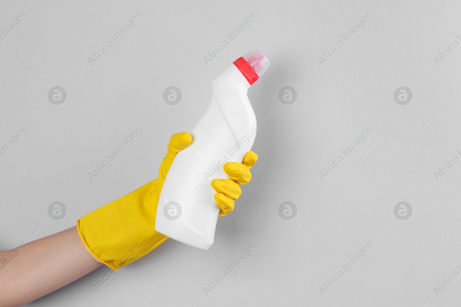 Photo of Woman holding toilet cleaner in bottle on light background, closeup. Space for text