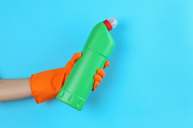 Photo of Woman holding toilet cleaner in bottle on light blue background, closeup. Space for text