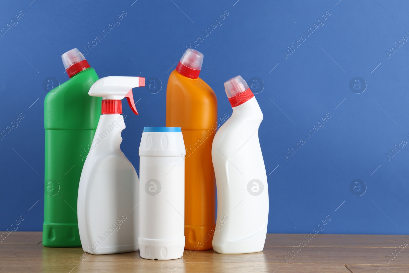 Photo of Different toilet cleaners on wooden table against blue background. Space for text