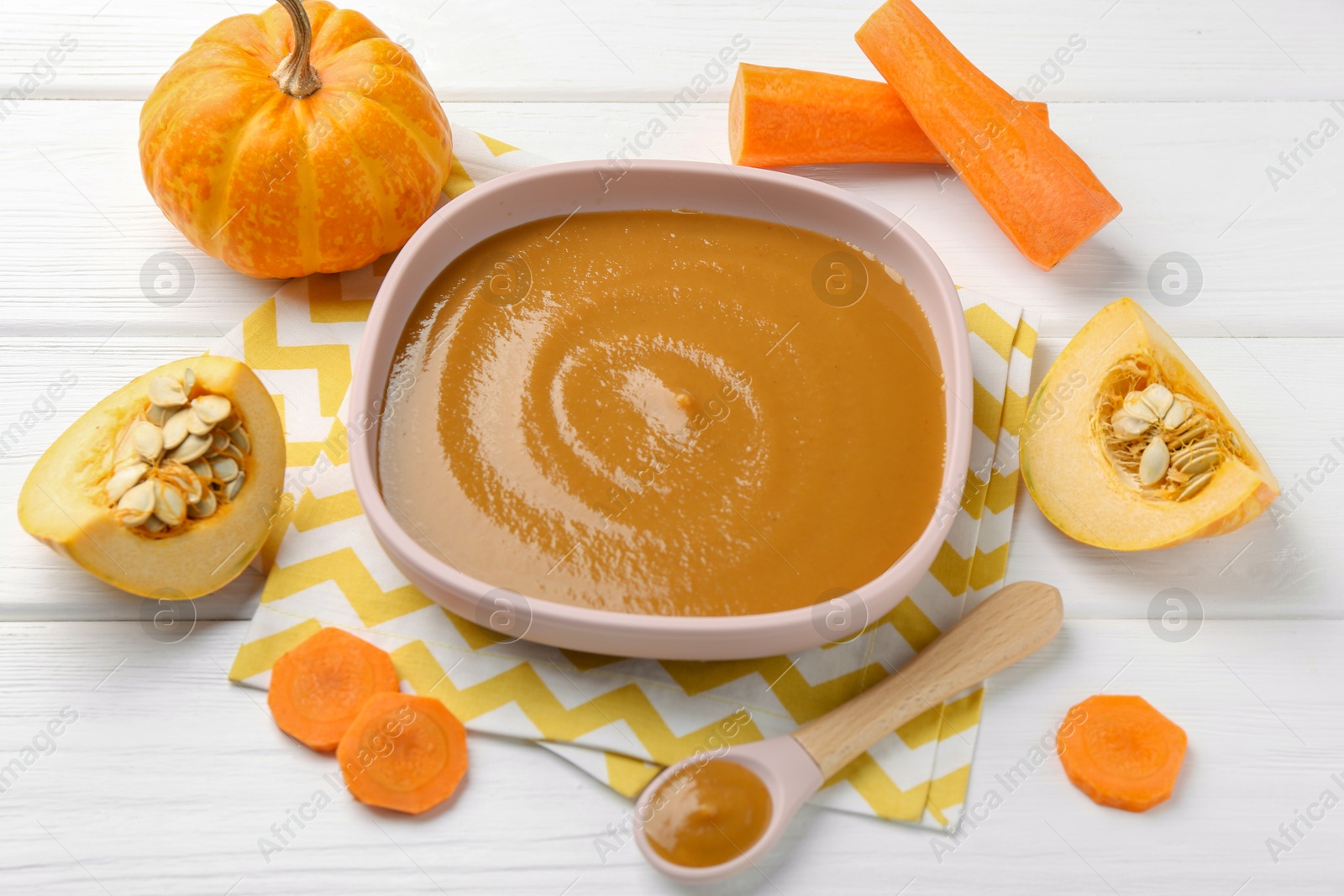 Photo of Delicious baby food in bowl and ingredients on white wooden table