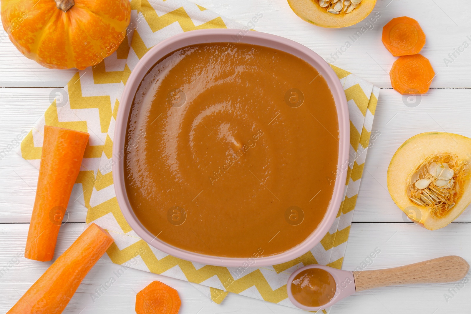 Photo of Delicious baby food in bowl and ingredients on white wooden table, flat lay