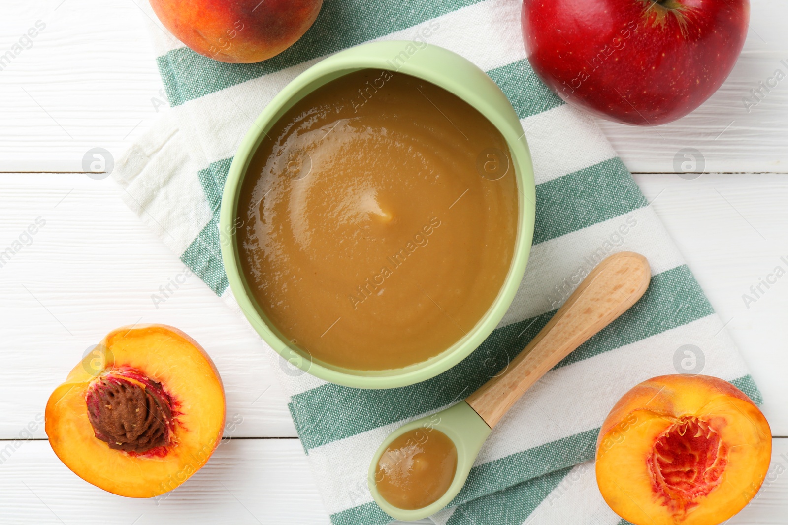 Photo of Delicious baby food in bowl and ingredients on white wooden table, flat lay