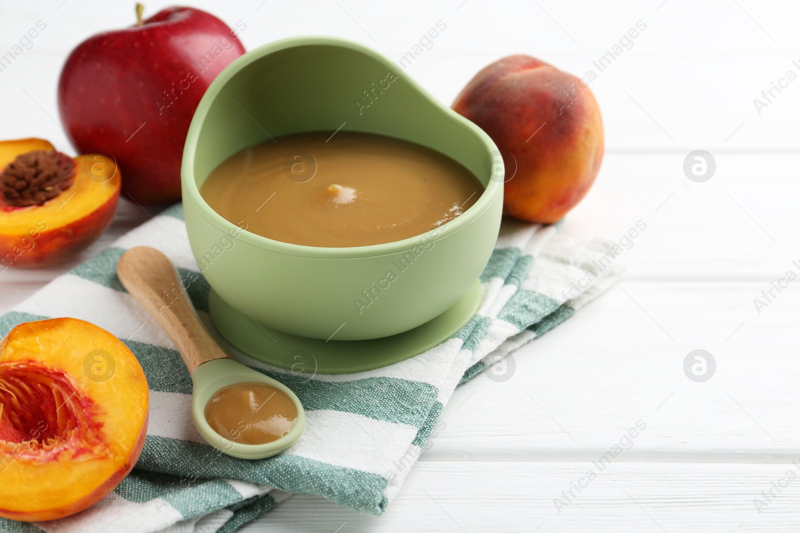 Photo of Delicious baby food in bowl and ingredients on white wooden table, closeup