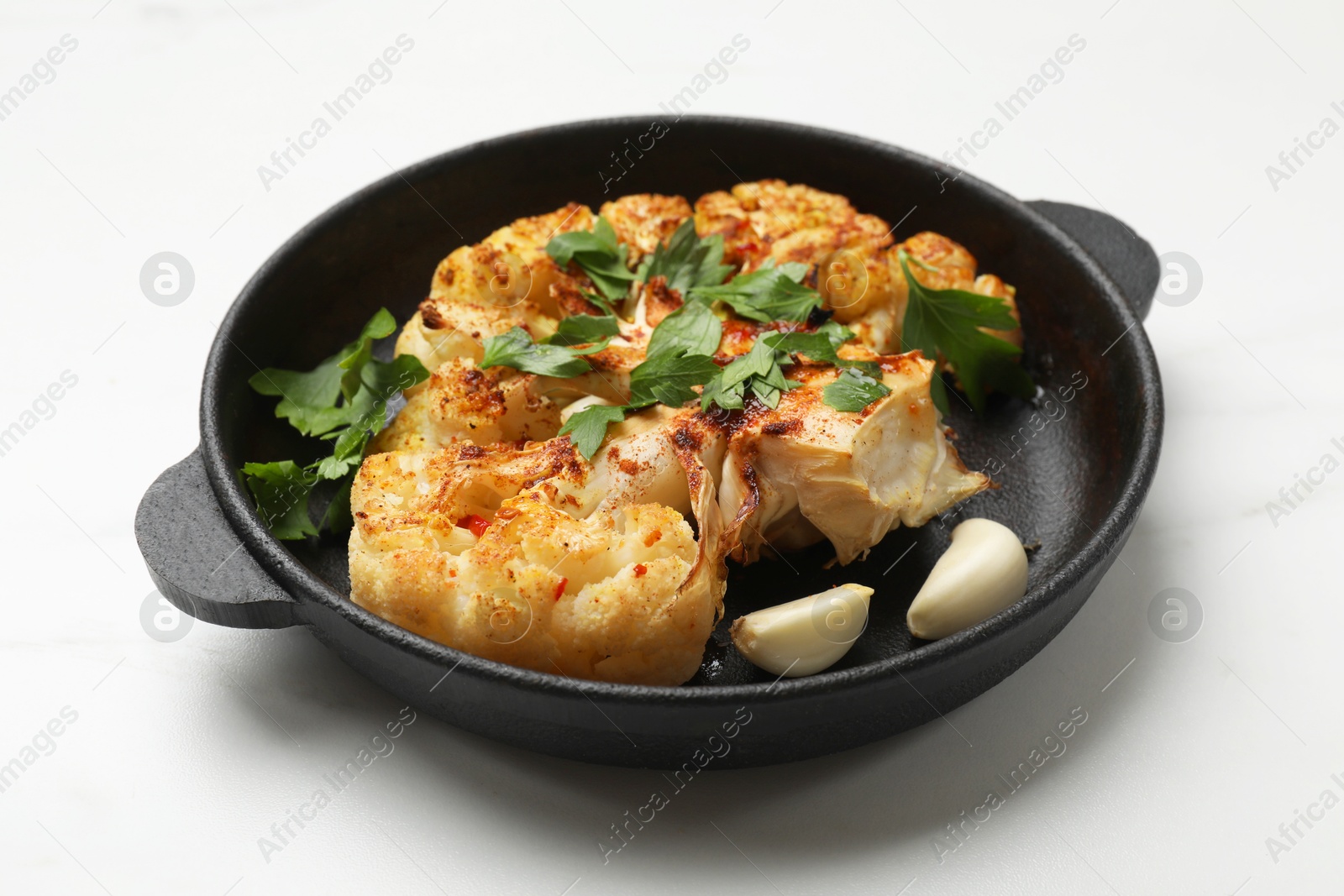 Photo of Tasty cauliflower steak in frying pan on white table, closeup