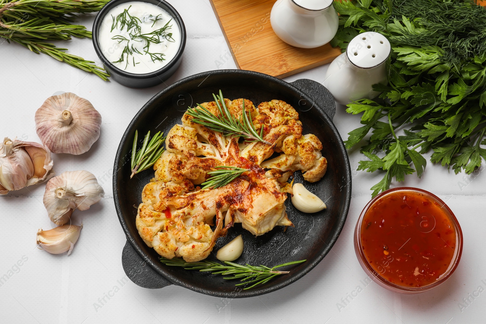 Photo of Delicious baked cauliflower steaks served on white tiled table, flat lay