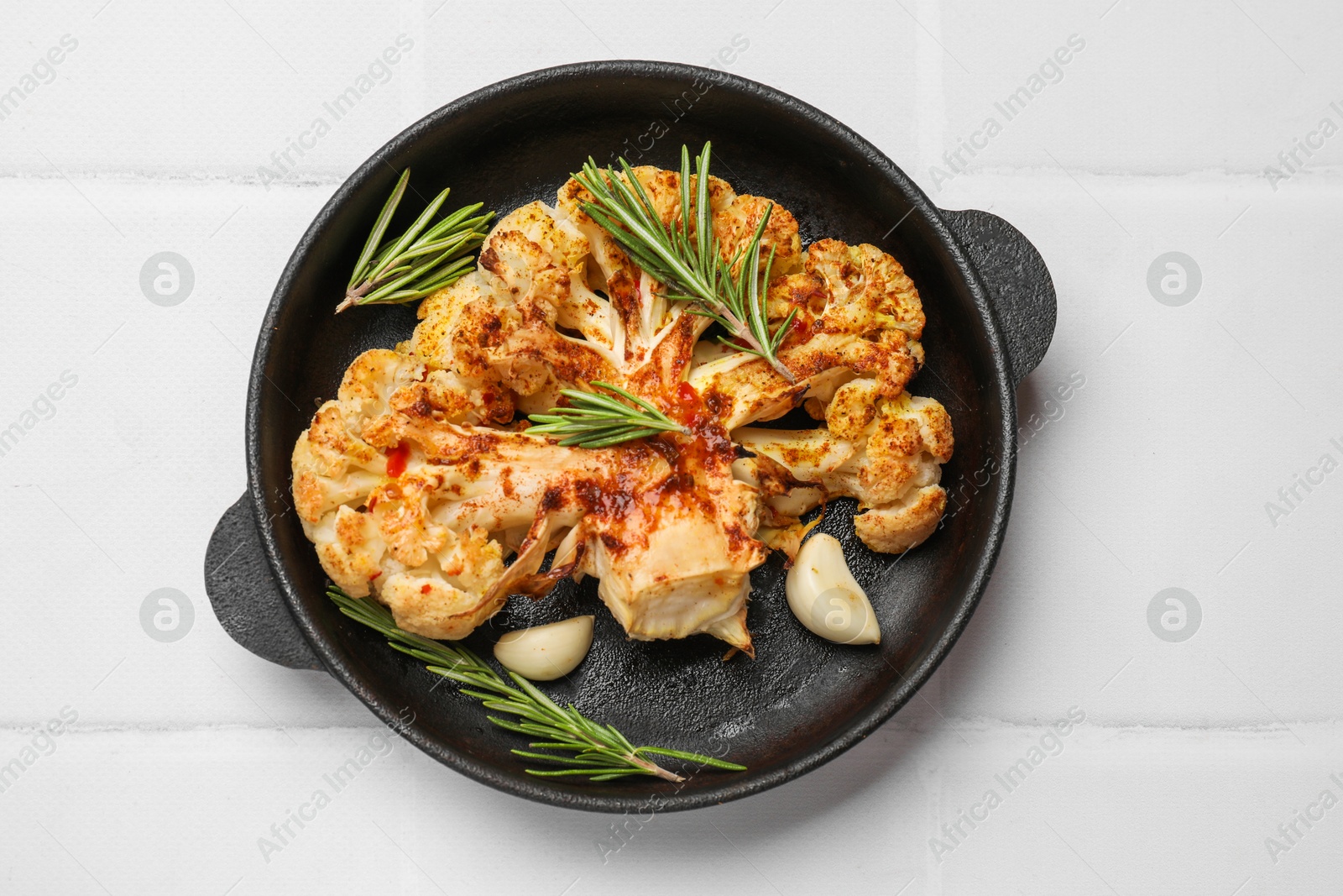 Photo of Delicious baked cauliflower steaks on white tiled table, top view