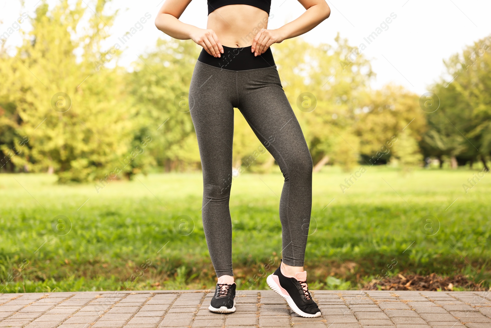 Photo of Woman wearing stylish sports leggings outdoors, closeup