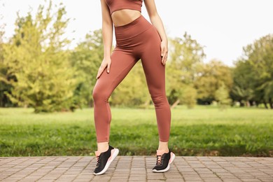 Photo of Woman wearing stylish sports leggings outdoors, closeup