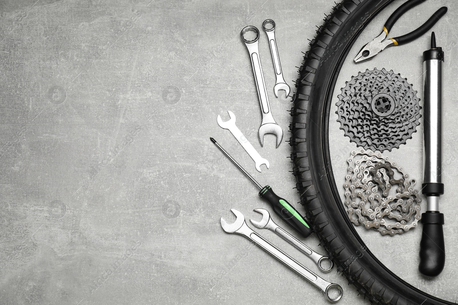 Photo of Parts of bicycle and tools on light grey table, flat lay. Space for text