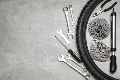 Parts of bicycle and tools on light grey table, flat lay. Space for text