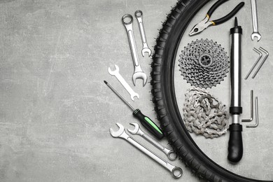 Parts of bicycle and tools on light grey table, flat lay. Space for text