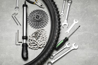 Parts of bicycle and tools on light grey table, flat lay