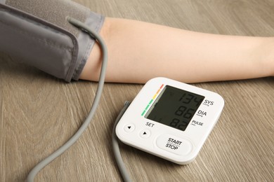 Woman measuring blood pressure at wooden table, closeup