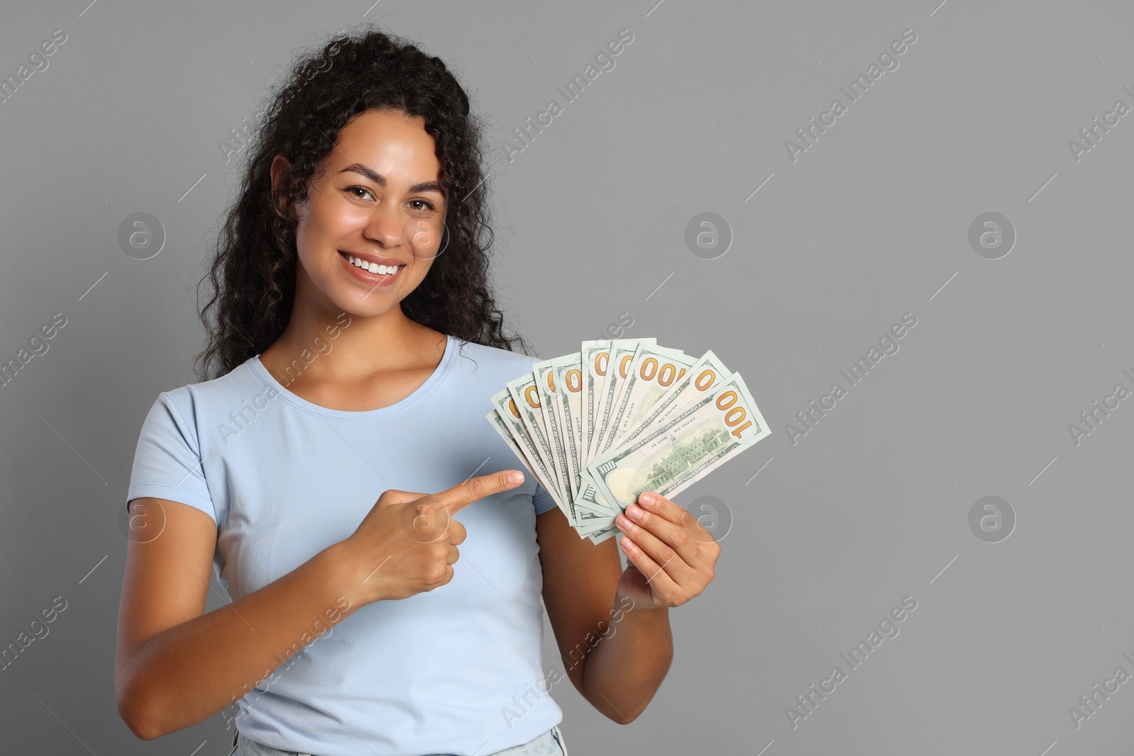 Photo of Happy woman with dollar banknotes on grey background, space for text