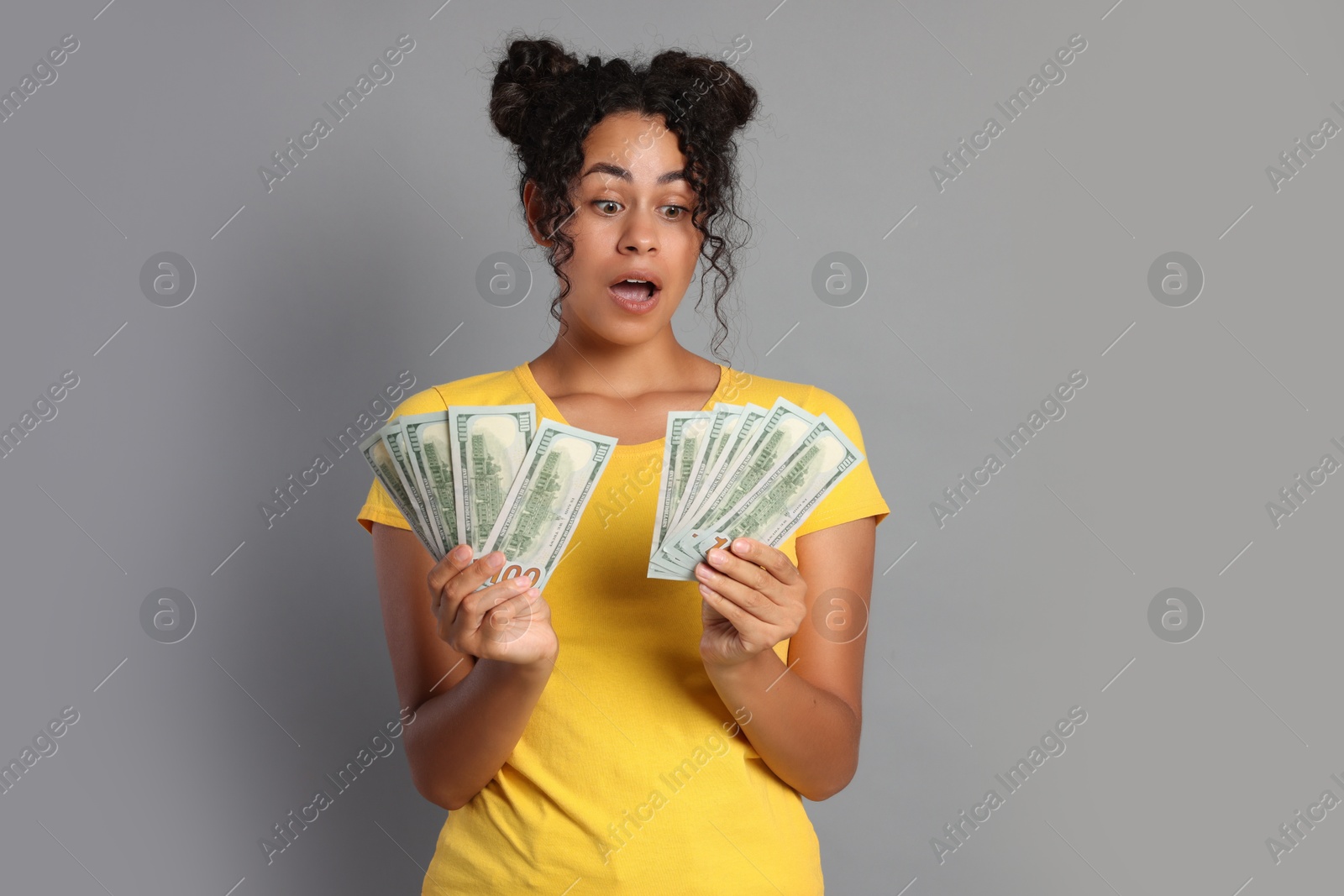 Photo of Shocked woman with dollar banknotes on grey background