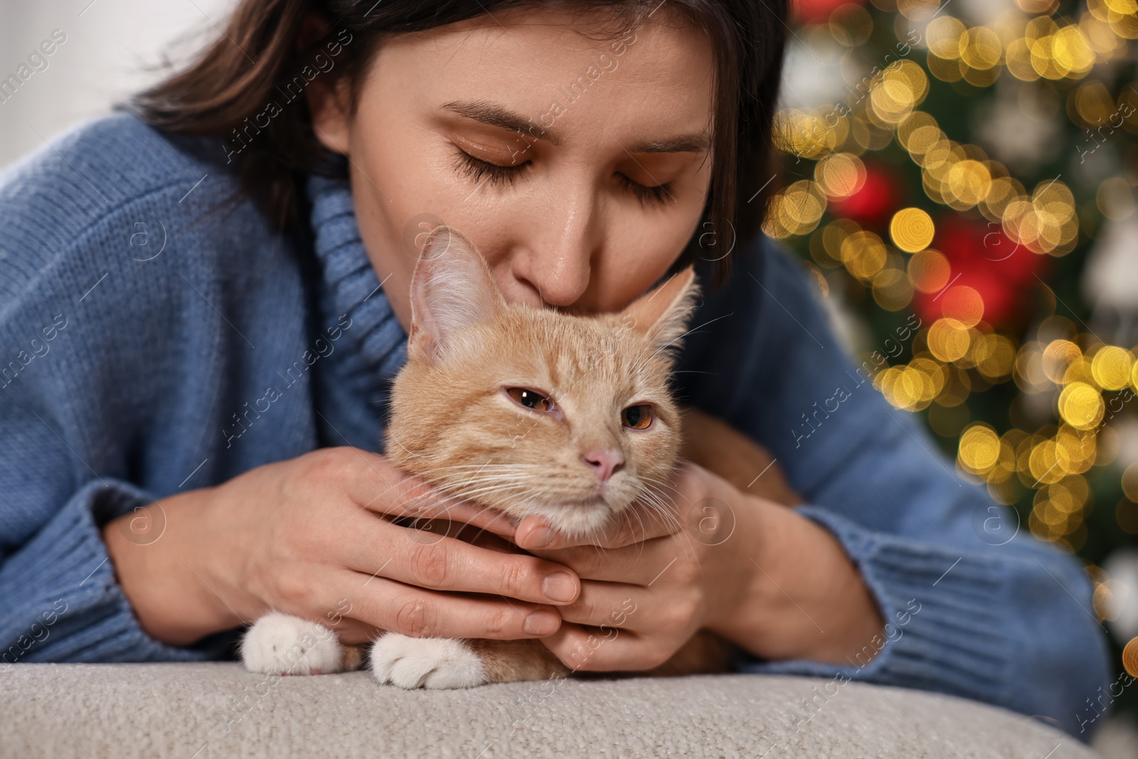 Photo of Woman with cute ginger cat in room decorated for Christmas