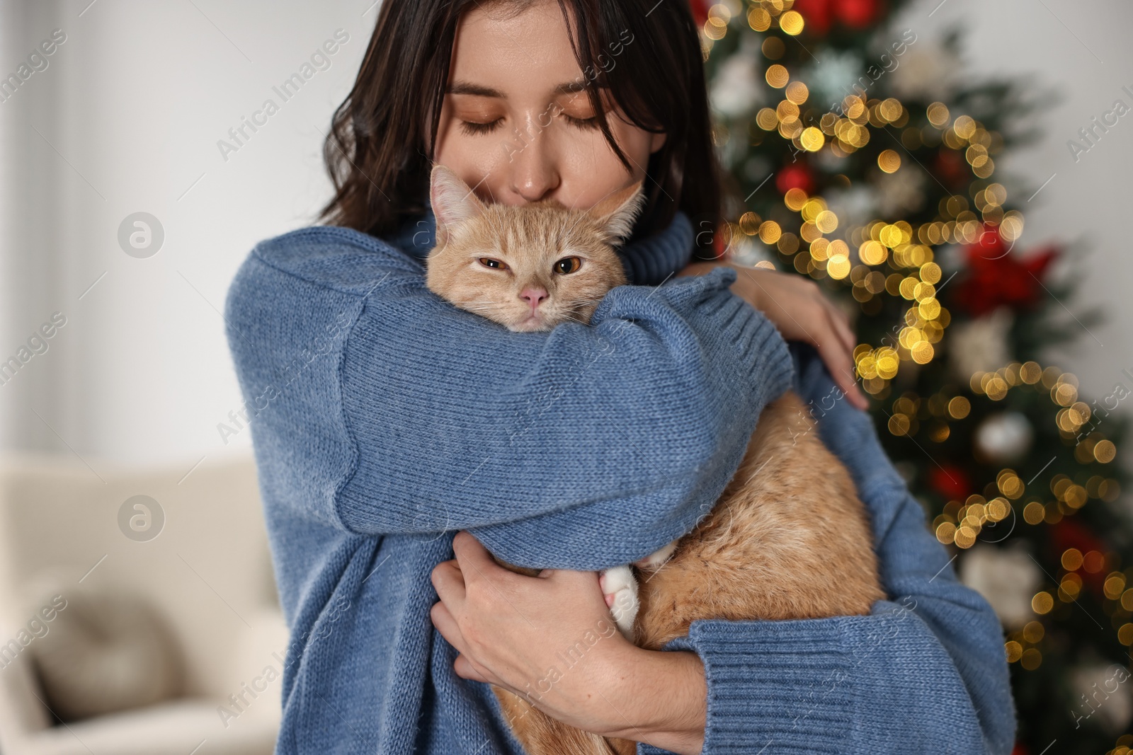 Photo of Woman with cute ginger cat in room decorated for Christmas