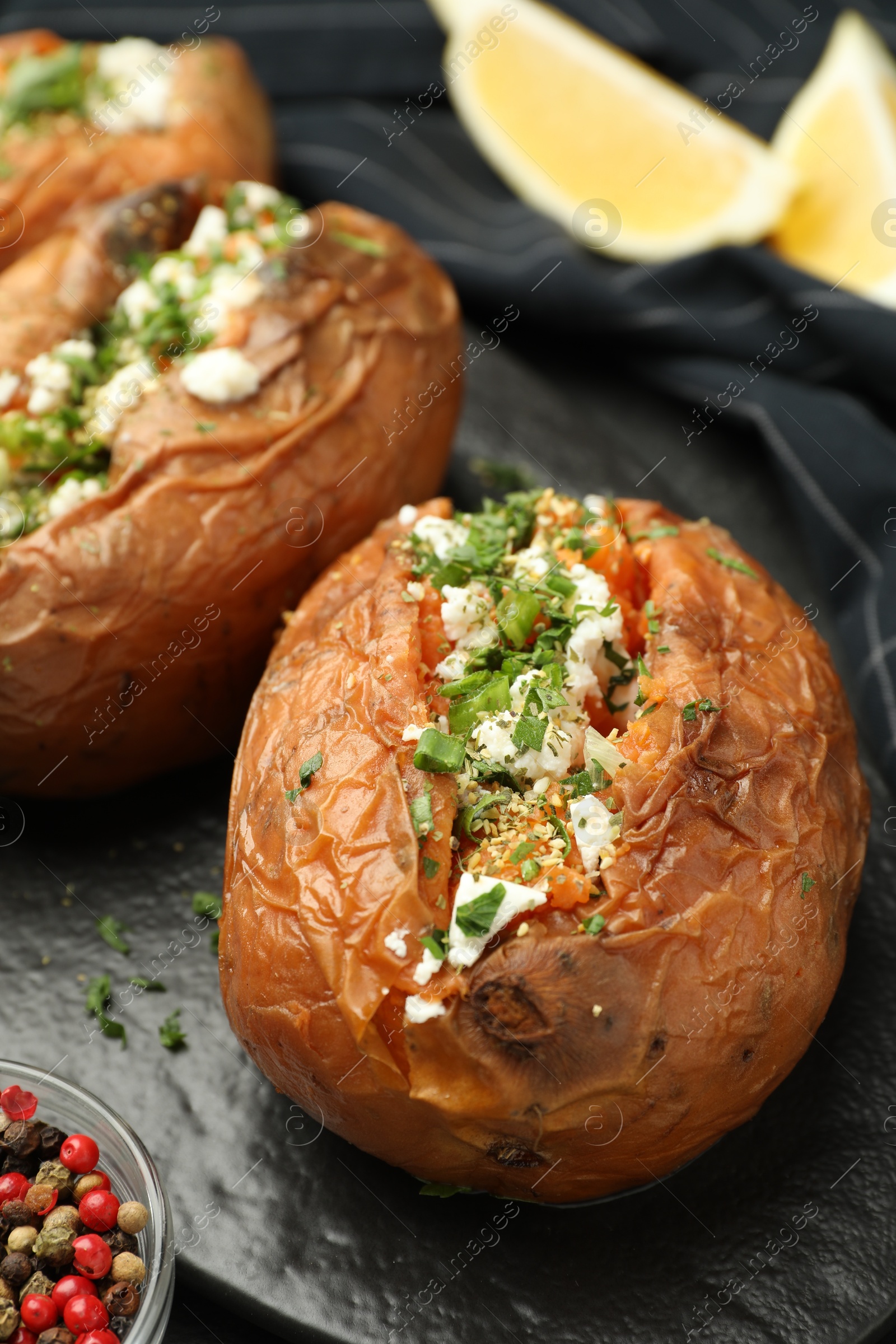 Photo of Tasty baked sweet potatoes with feta cheese and parsley on table, closeup