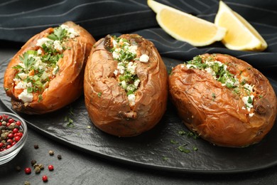 Photo of Tasty baked sweet potatoes with feta cheese and parsley on dark table, closeup