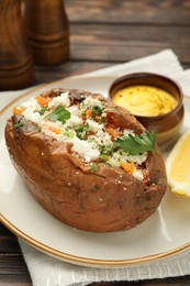 Photo of Tasty baked sweet potato with feta cheese, parsley and sauce on wooden table, closeup