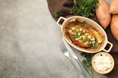 Tasty baked sweet potato with feta cheese and herbs on grey textured table, flat lay. Space for text