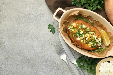 Photo of Tasty baked sweet potato with feta cheese and herbs on grey textured table, flat lay. Space for text