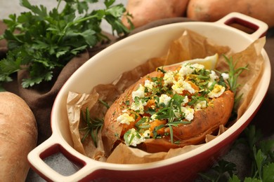 Photo of Tasty baked sweet potato with feta cheese and herbs on table, closeup