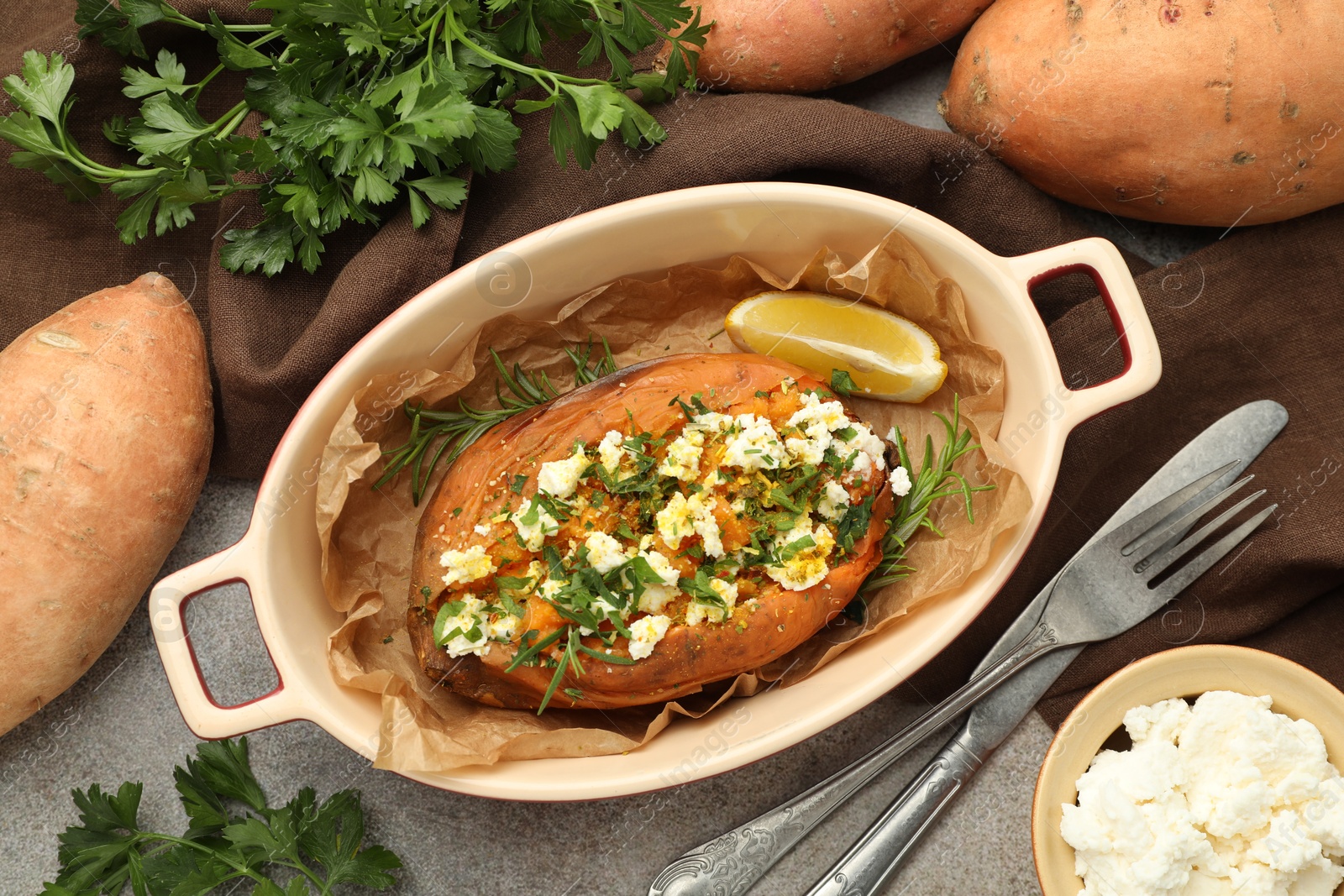 Photo of Tasty baked sweet potato with feta cheese and herbs on grey textured table, flat lay