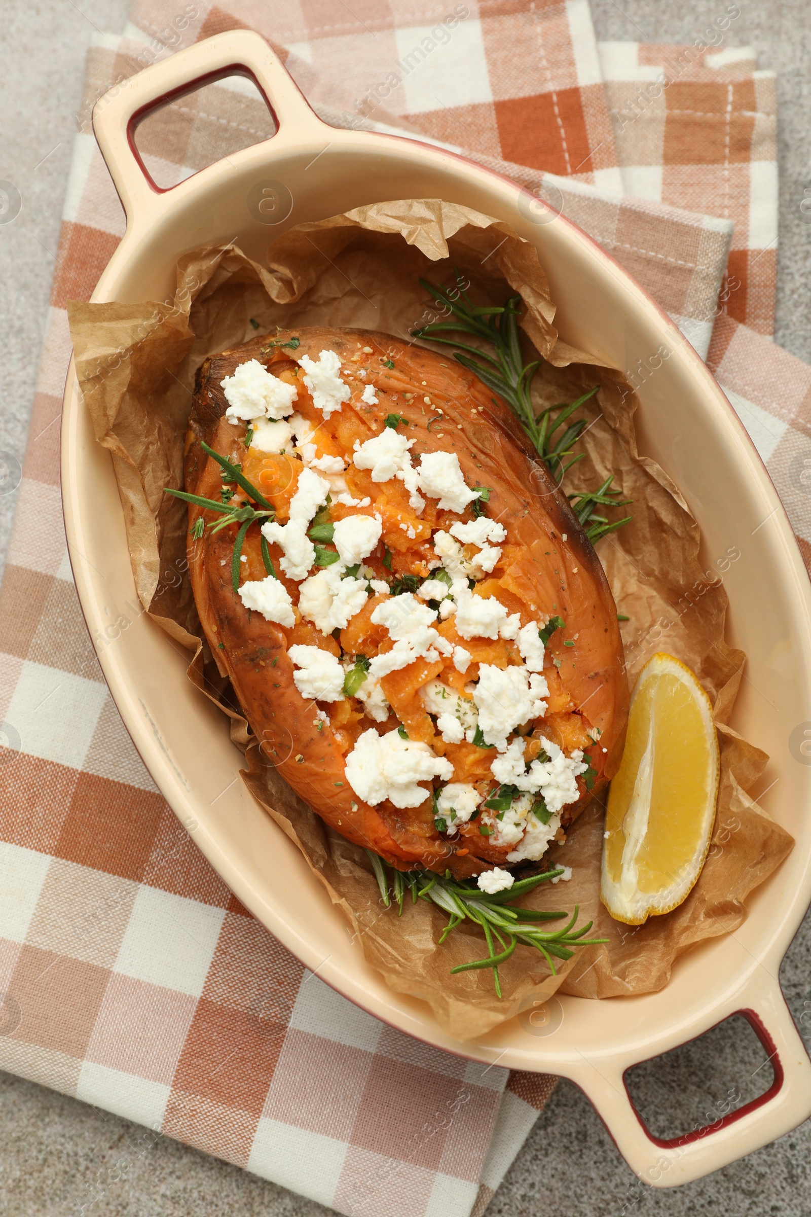 Photo of Tasty baked sweet potato with feta cheese, lemon and herbs on grey textured table, top view