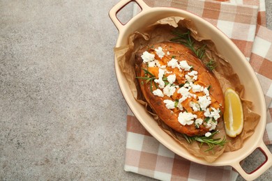 Photo of Tasty baked sweet potato with feta cheese, lemon and herbs on grey textured table, top view. Space for text