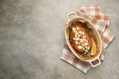 Tasty baked sweet potato with feta cheese, lemon and herbs on grey textured table, top view. Space for text