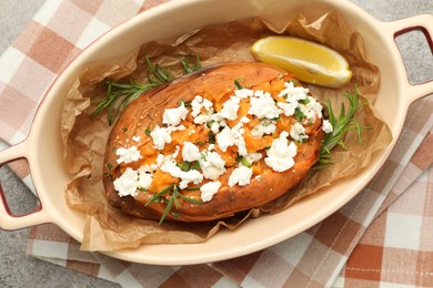 Photo of Tasty baked sweet potato with feta cheese, lemon and herbs on grey textured table, top view