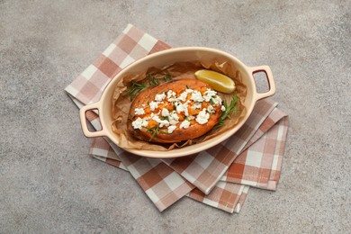 Tasty baked sweet potato with feta cheese, lemon and herbs on grey textured table, top view