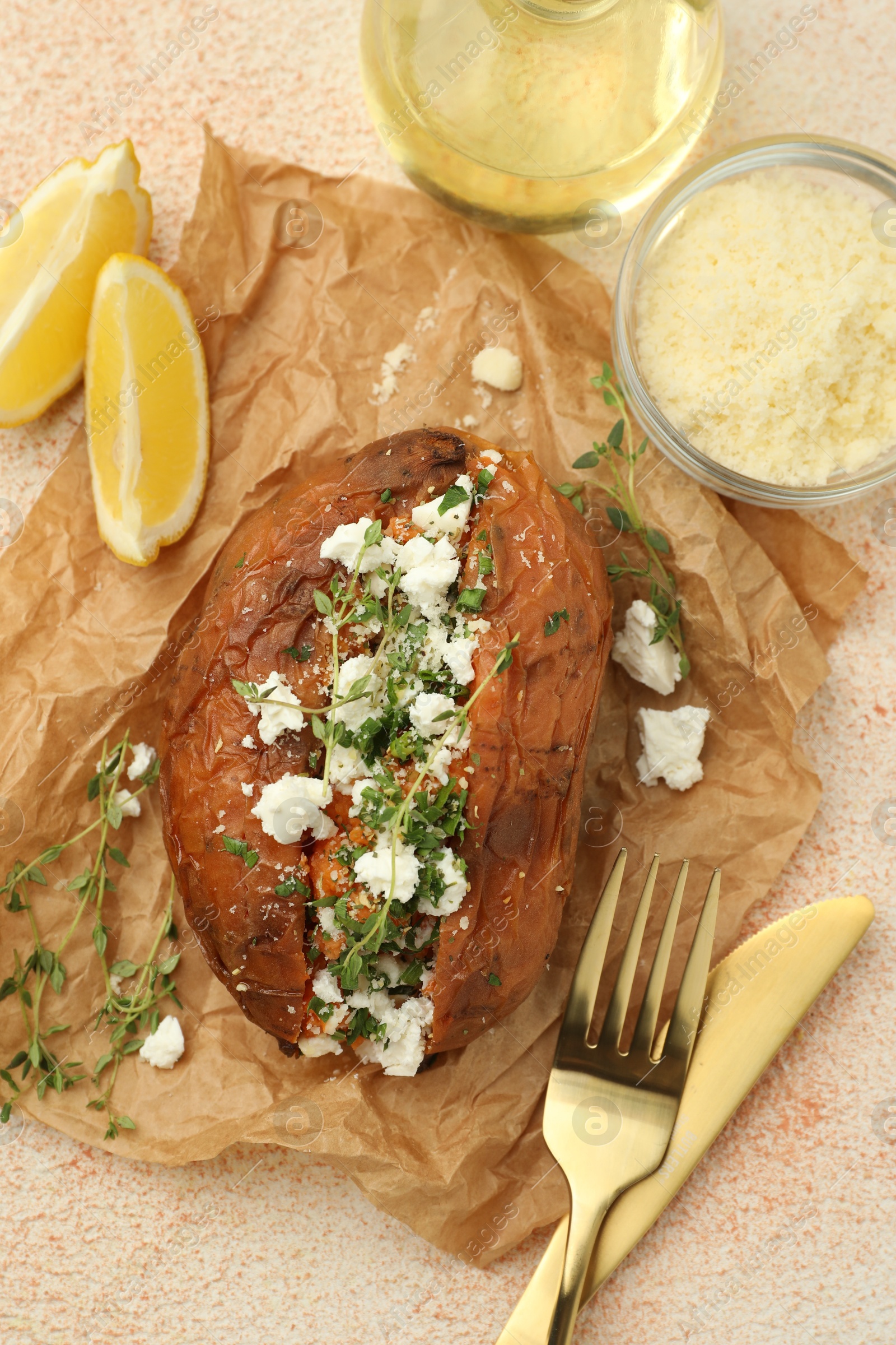 Photo of Tasty baked sweet potato with feta cheese, lemon and herbs on light textured table, flat lay