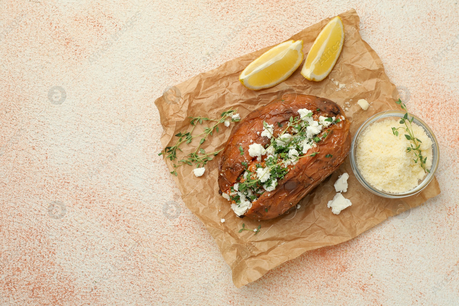 Photo of Tasty baked sweet potato with feta cheese, lemon and herbs on light textured table, top view. Space for text