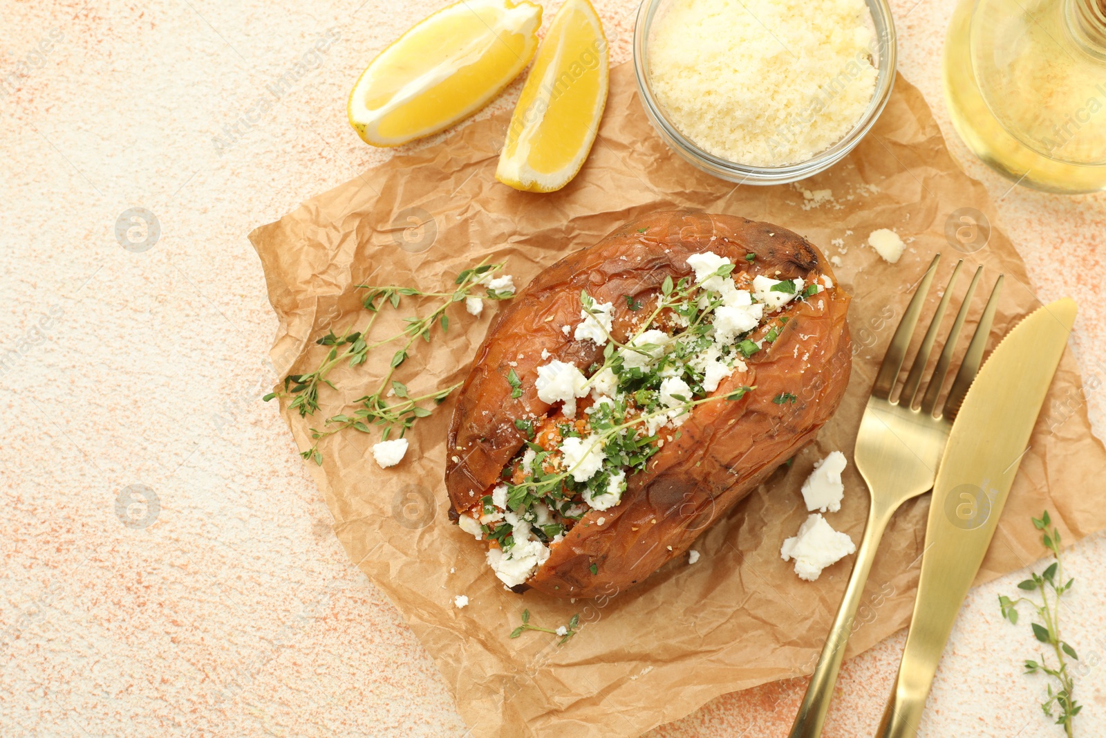 Photo of Tasty baked sweet potato with feta cheese, lemon and herbs on light textured table, top view. Space for text