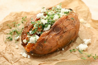 Photo of Tasty baked sweet potato with feta cheese and herbs on table, closeup