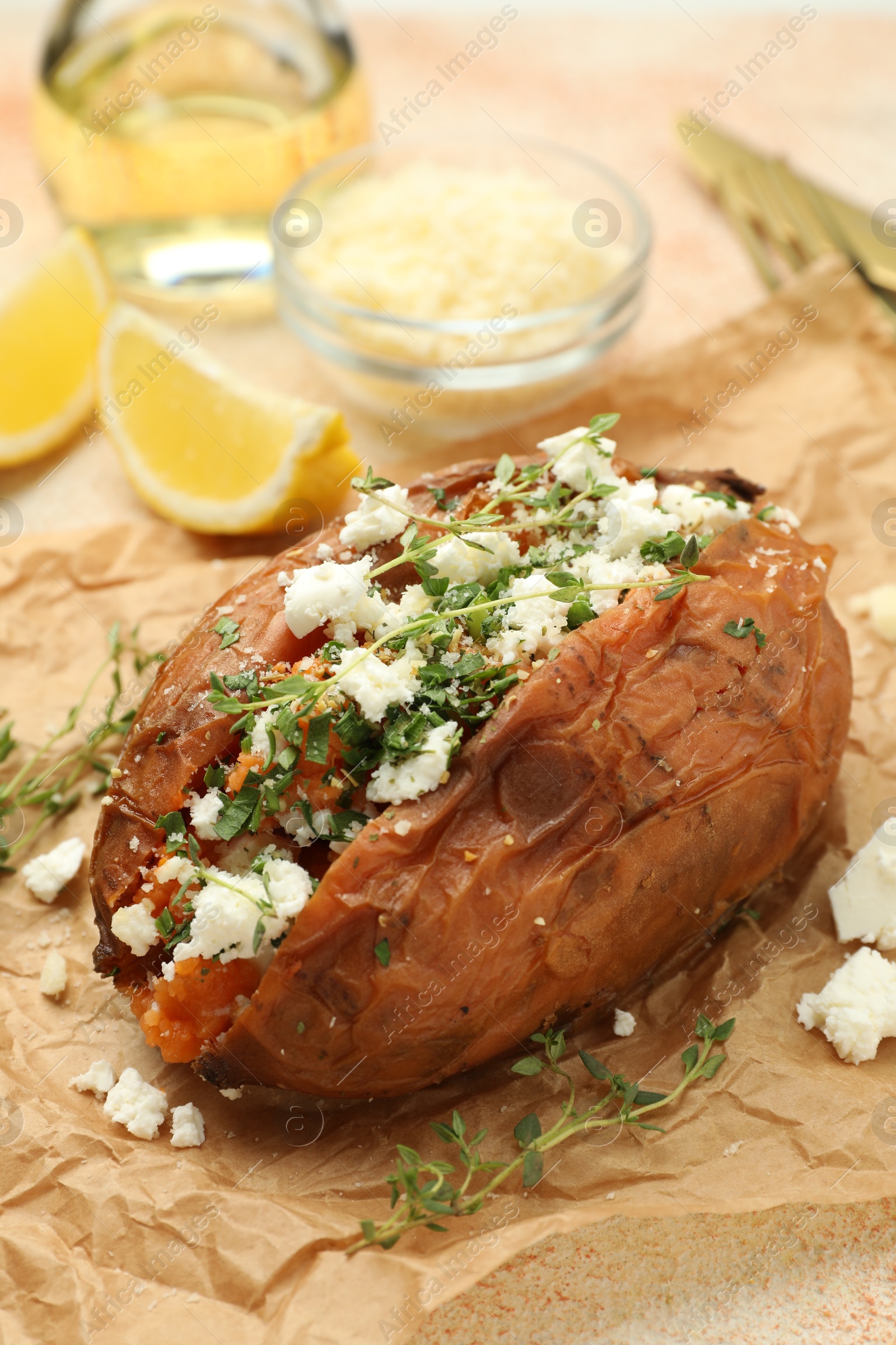 Photo of Tasty baked sweet potato with feta cheese and herbs on light textured table, closeup