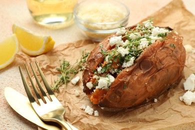 Photo of Tasty baked sweet potato with feta cheese and herbs on light textured table, closeup