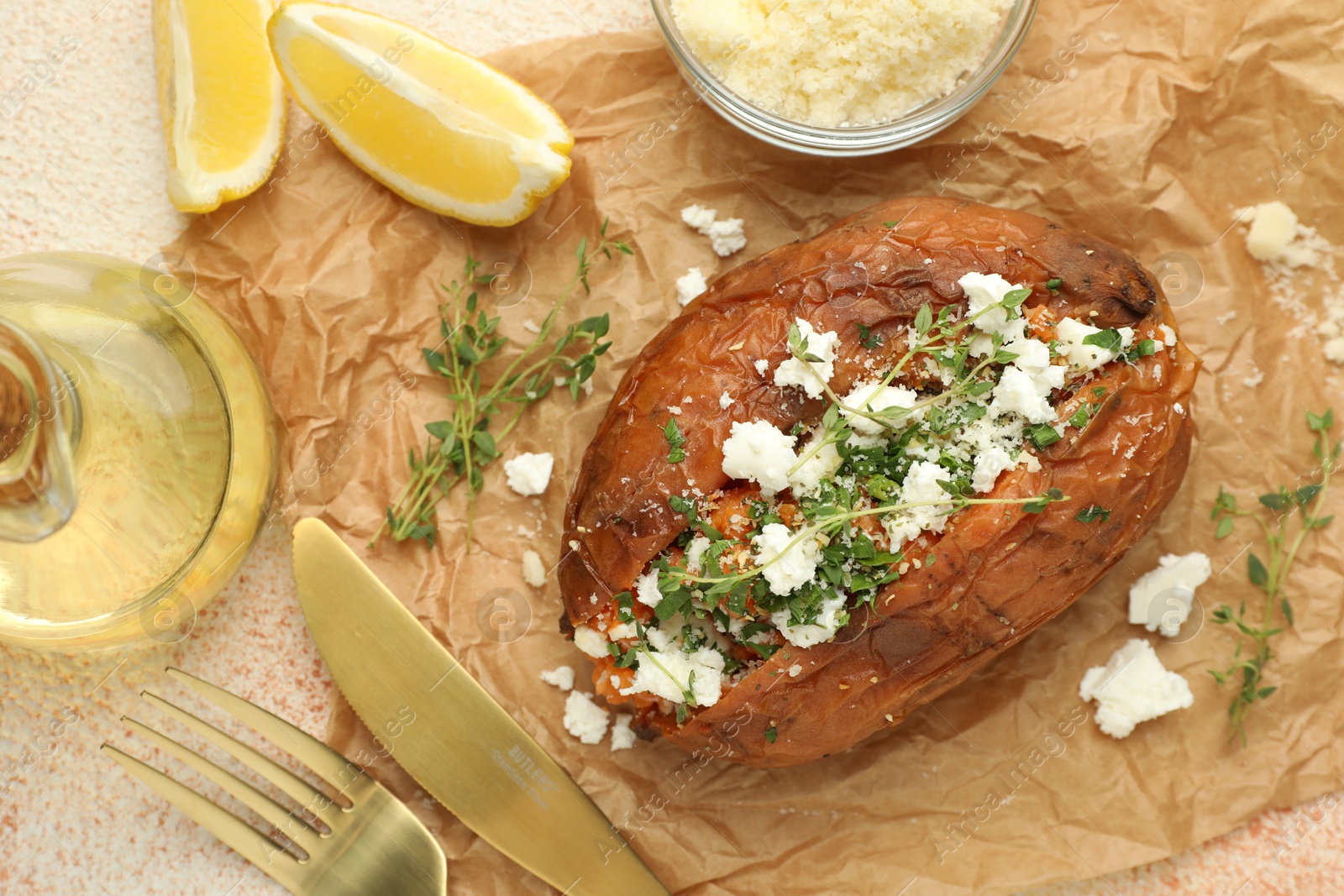 Photo of Tasty baked sweet potato with feta cheese, lemon and herbs on light textured table, flat lay