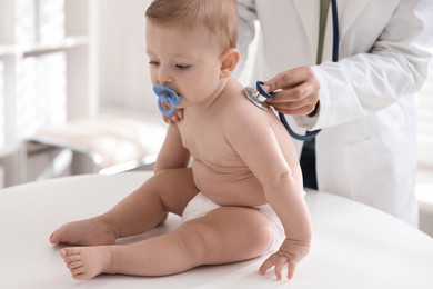 Photo of Pediatrician examining little child with stethoscope in clinic, closeup. Checking baby's health