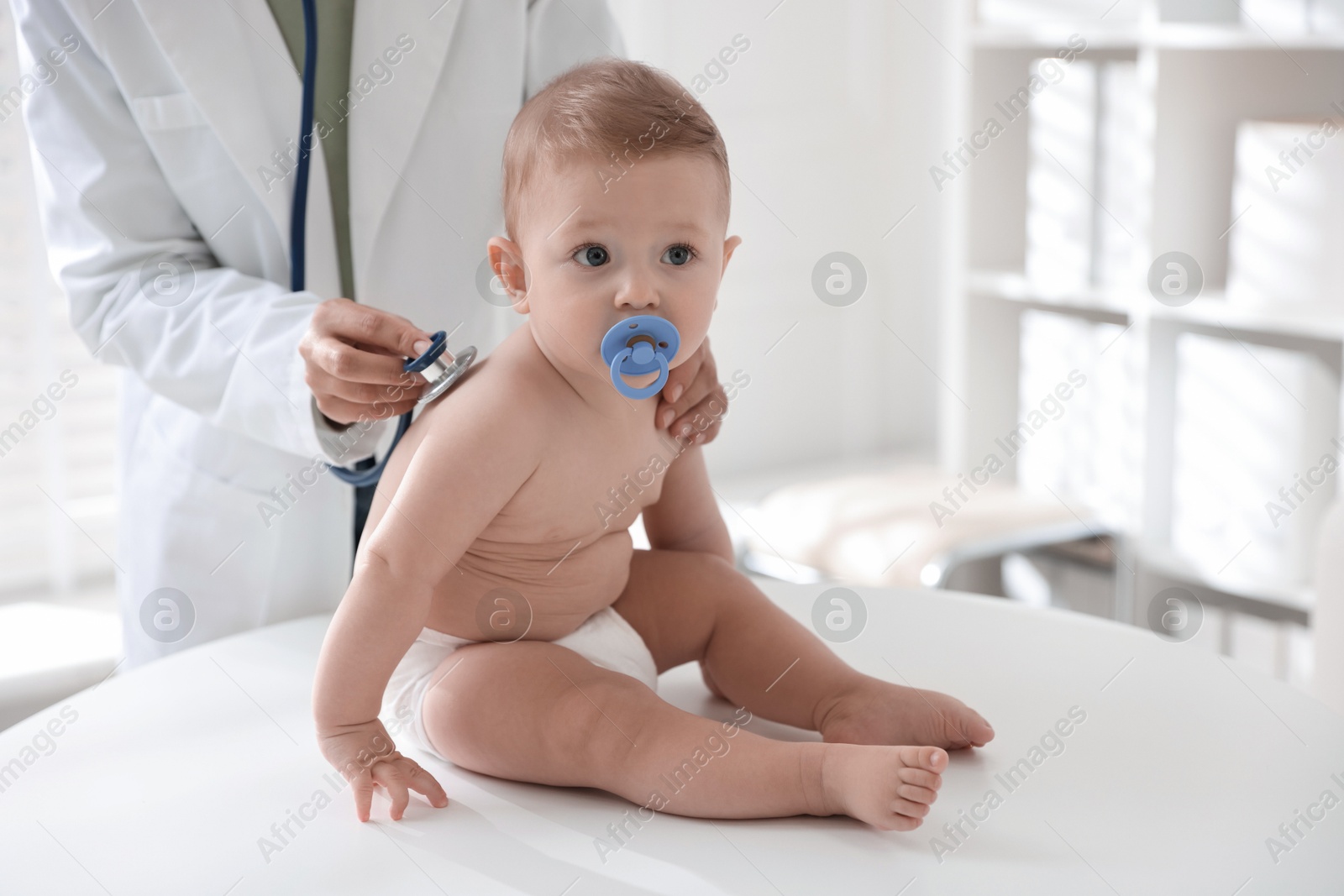 Photo of Pediatrician examining little child with stethoscope in clinic, closeup. Checking baby's health