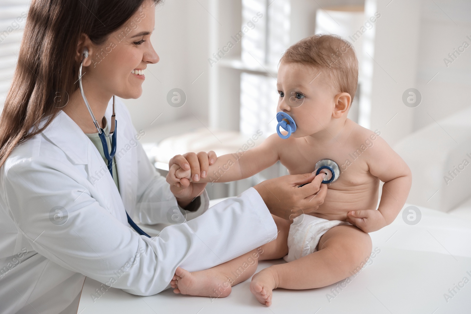 Photo of Pediatrician examining little child with stethoscope in clinic. Checking baby's health