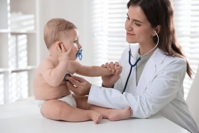 Photo of Pediatrician examining little child with stethoscope in clinic. Checking baby's health