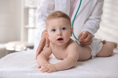 Photo of Pediatrician examining little child with stethoscope in clinic, closeup. Checking baby's health