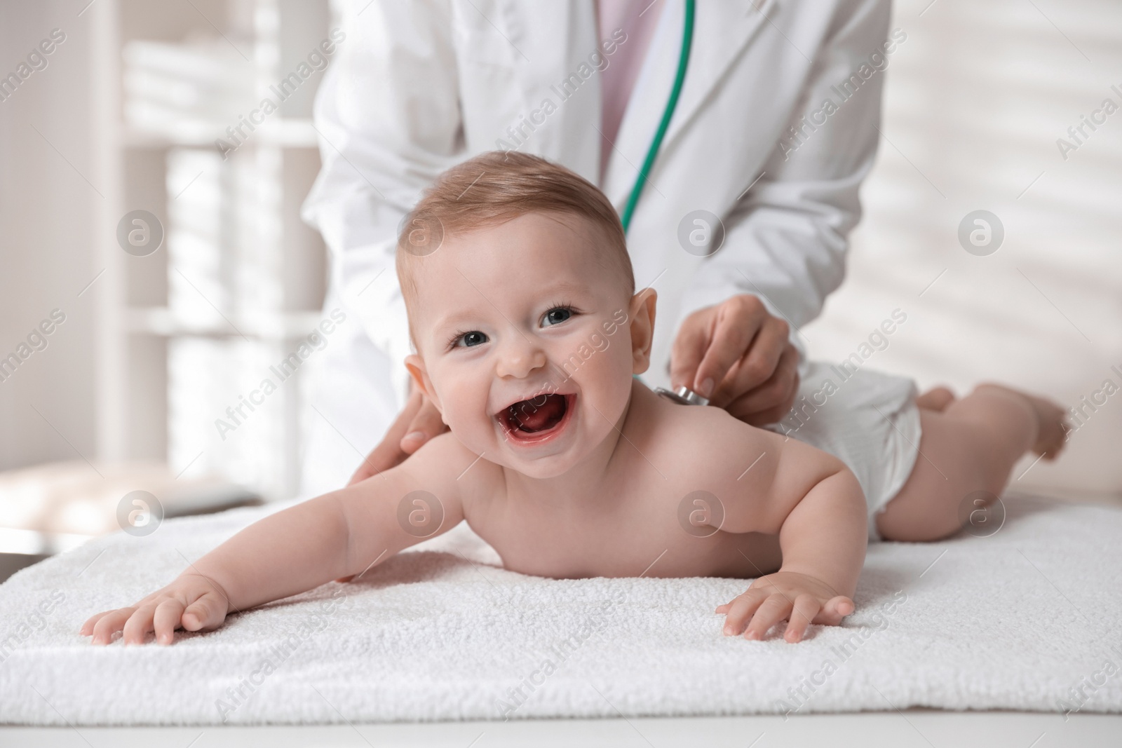 Photo of Pediatrician examining little child with stethoscope in clinic, closeup. Checking baby's health