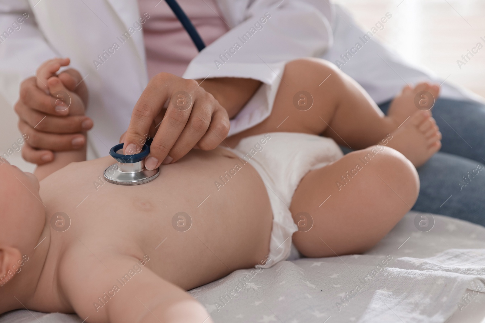 Photo of Pediatrician examining little child with stethoscope in clinic, closeup. Checking baby's health