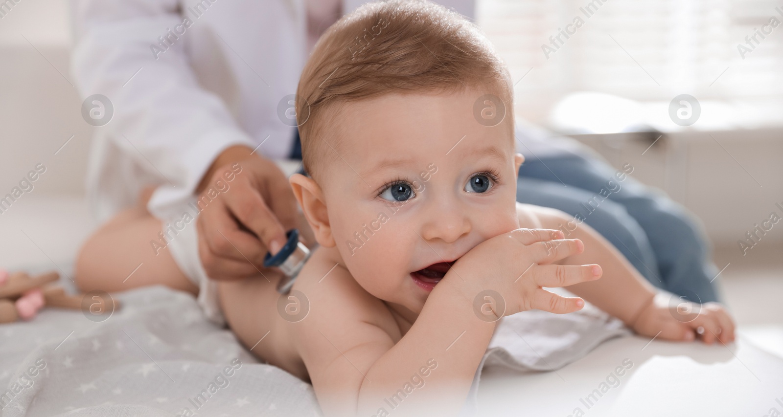 Photo of Pediatrician examining little child with stethoscope in clinic, closeup. Checking baby's health