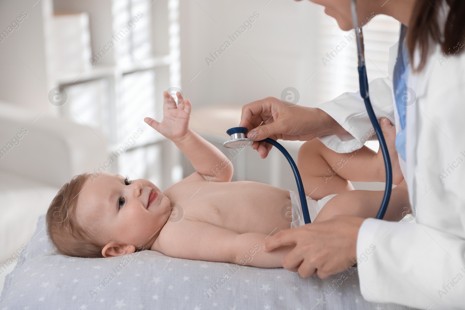 Photo of Pediatrician examining little child with stethoscope in clinic, closeup. Checking baby's health