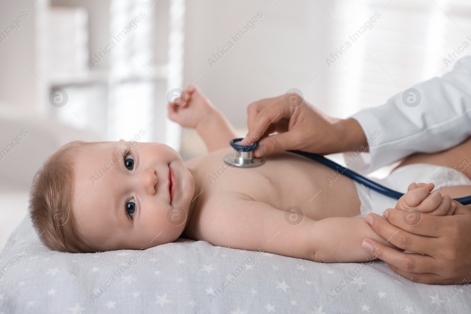 Photo of Pediatrician examining little child with stethoscope in clinic, closeup. Checking baby's health